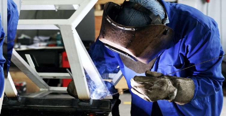 Welder completing a pipe joint on site