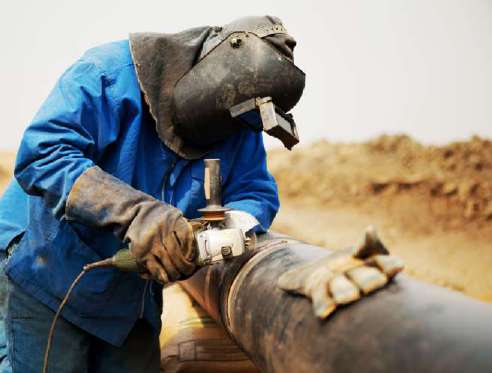 Welder completing a pipe joint on site